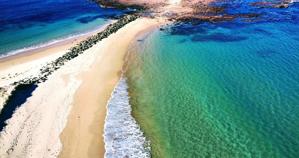 An Aerial View of a Sandy Beach Surrounded by Turquoise Water — South Coast Pressure Washer in Warilla, NSW