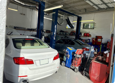 Cars in a garage, one lifted on a car lift. Tools and equipment visible. | Dave's Auto Repair
