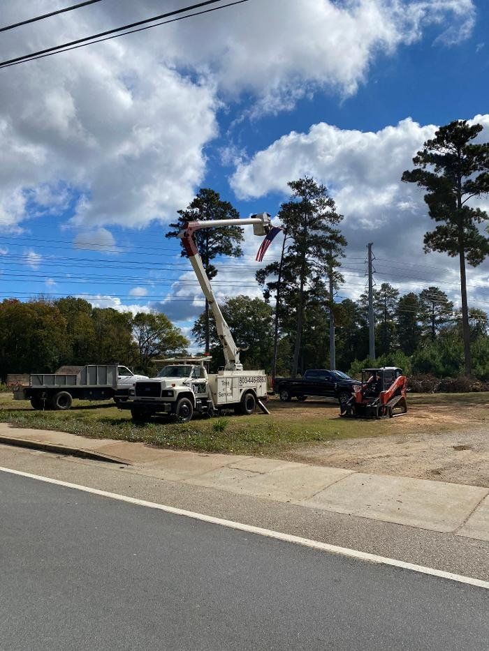 Power line crew using a boom truck to work on power lines, with a chipper and trucks in the background.