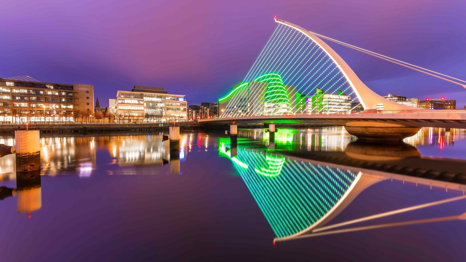 a bridge over a body of water is lit up at night and reflected in the water