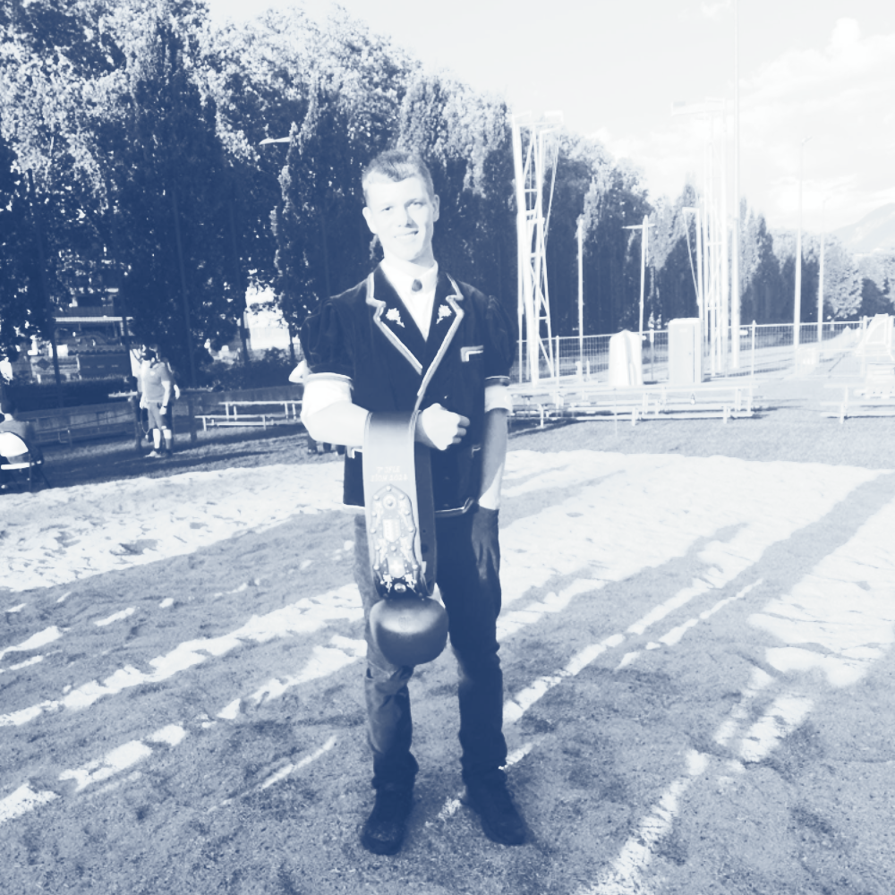 Eine Person steht im Freien und hält eine Glocke.