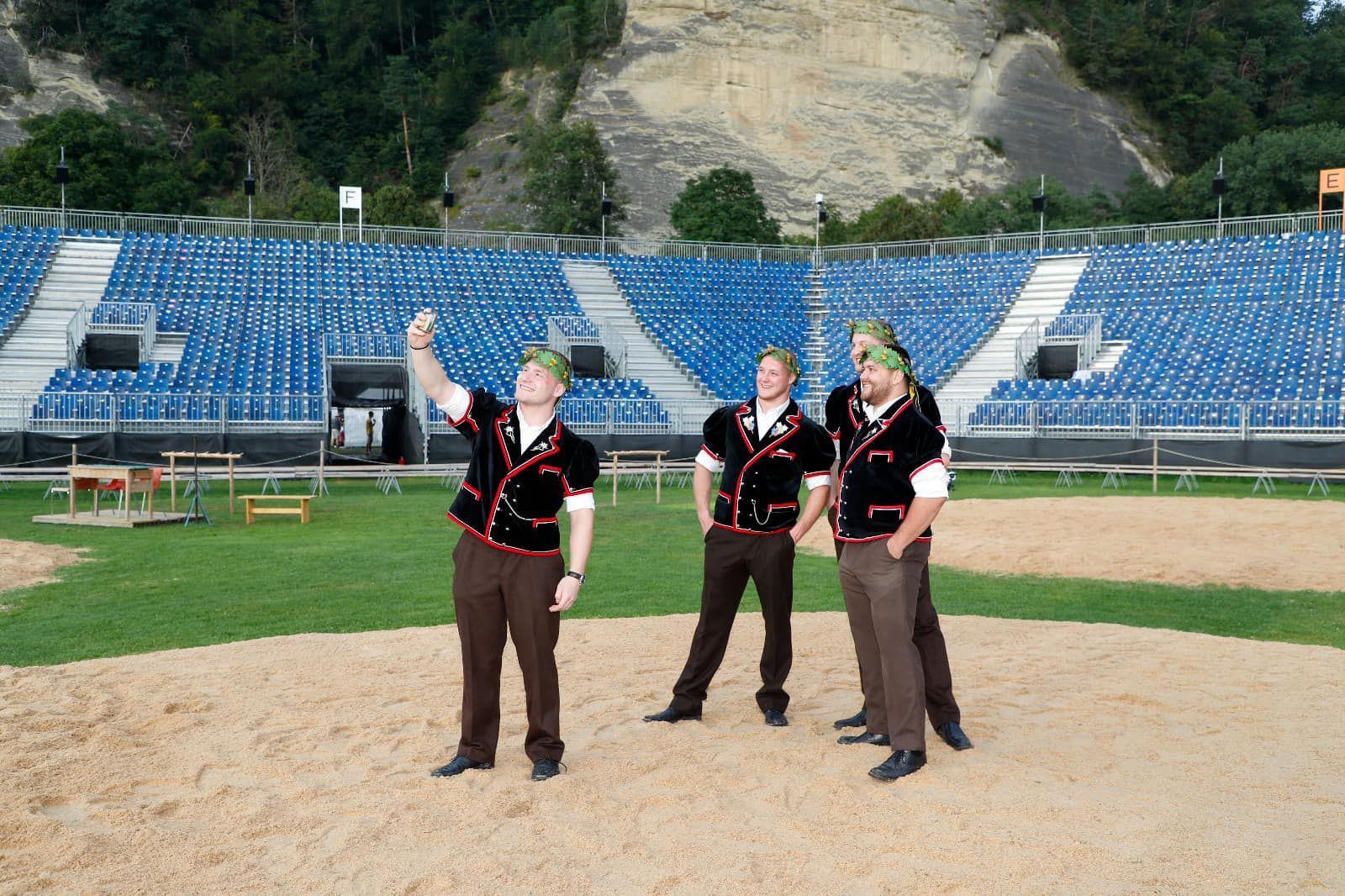 Männer in traditioneller Schweizer Tracht; im Hintergrund sind Tribünen zu sehen.