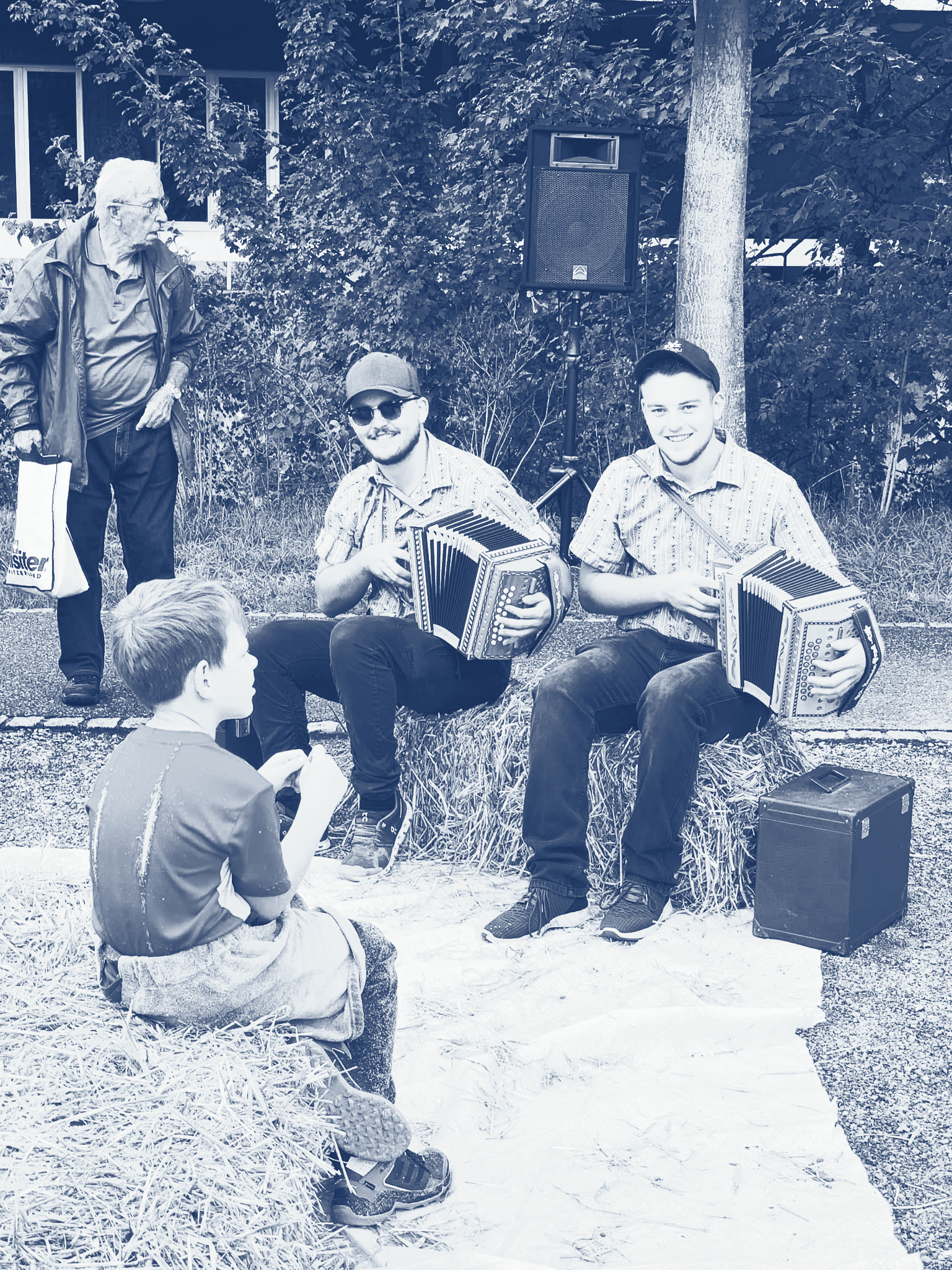 Menschen mit Akkordeons sitzen, ein weiterer Mann steht in der Nähe.