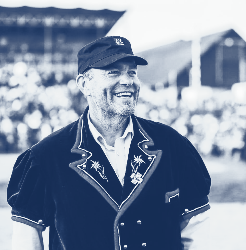 Mann in traditioneller Schweizer Tracht lächelt im Freien bei einer Veranstaltung.