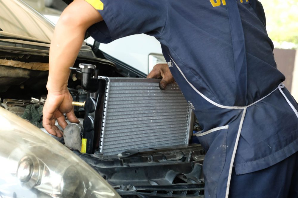 Mecánico instalando un radiador en el compartimento del motor de un coche