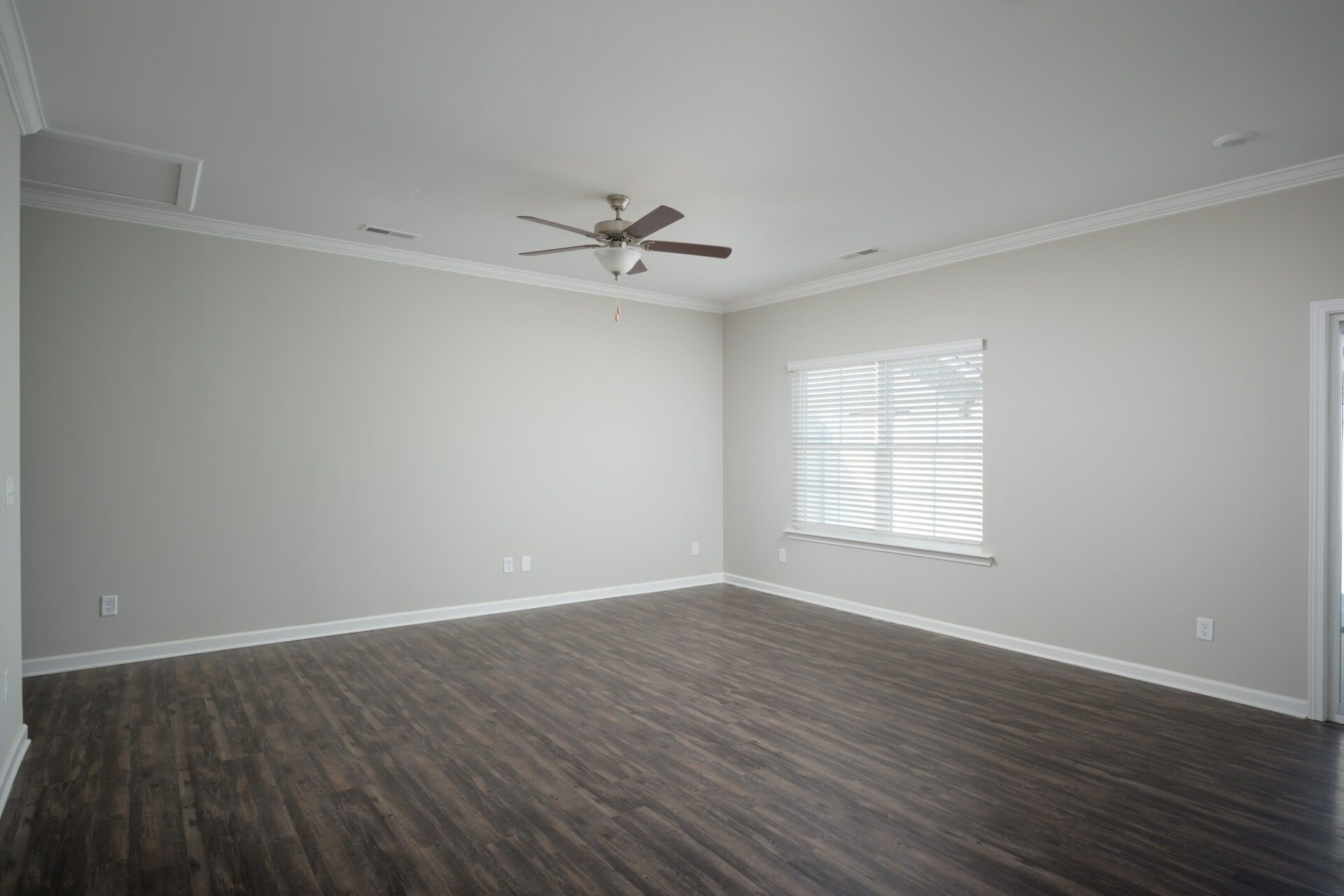 An empty living room with a ceiling fan and a window at Ashford Villas in Chattanooga, TN.
