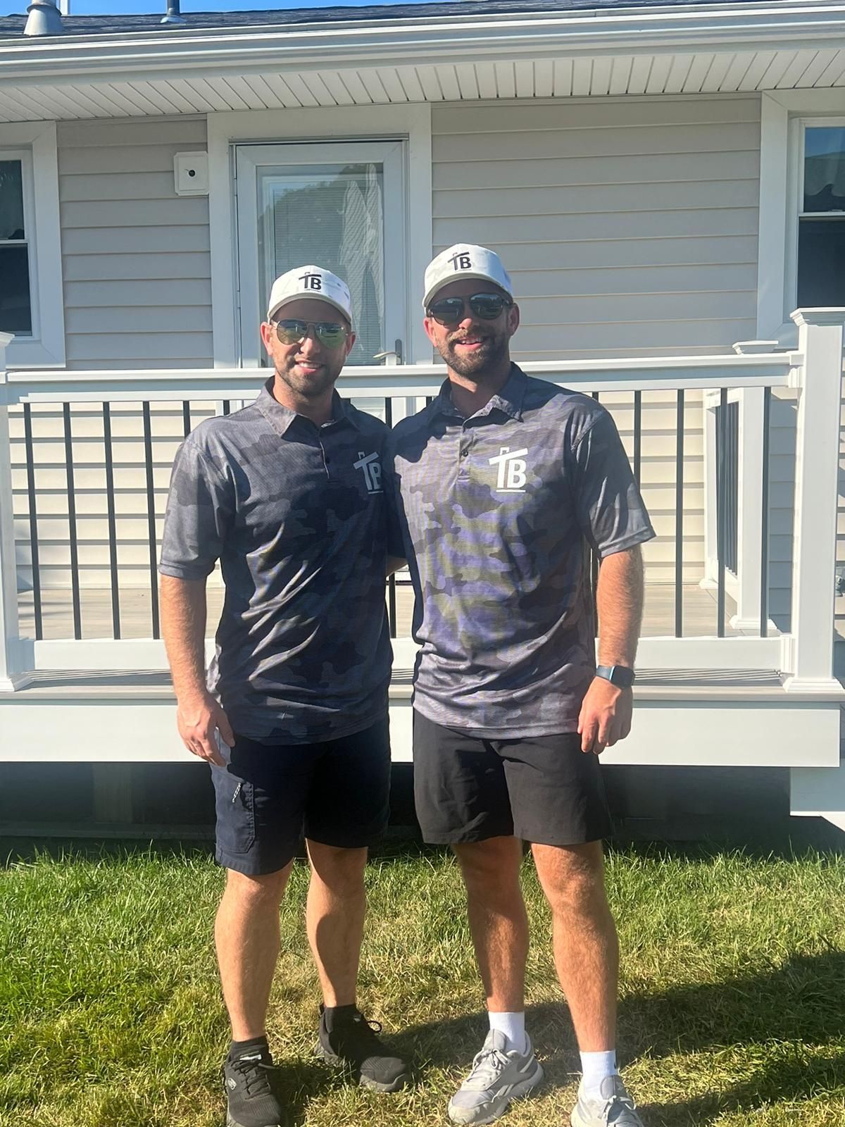 Two men are standing next to each other in front of a house.