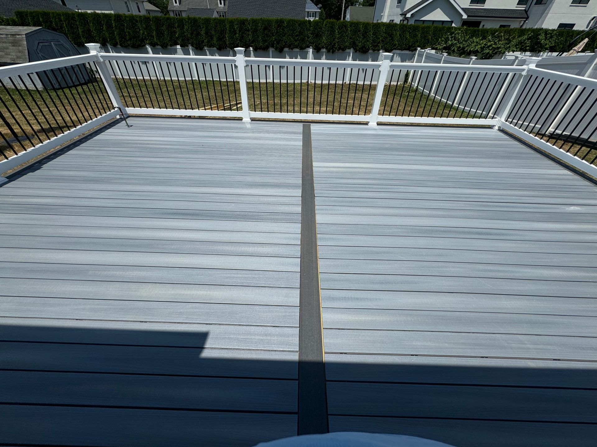 A wooden deck with a white railing and a white fence