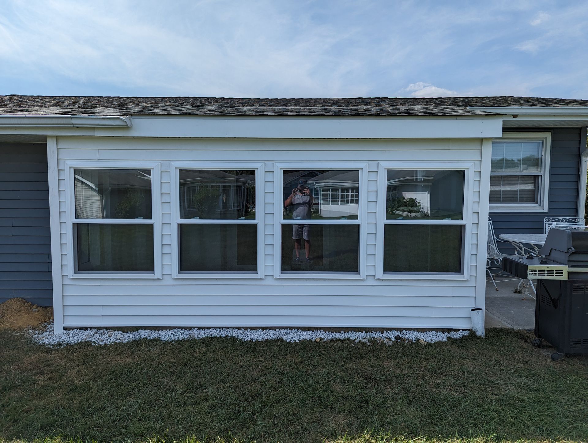 A house with a lot of windows and a grill in front of it