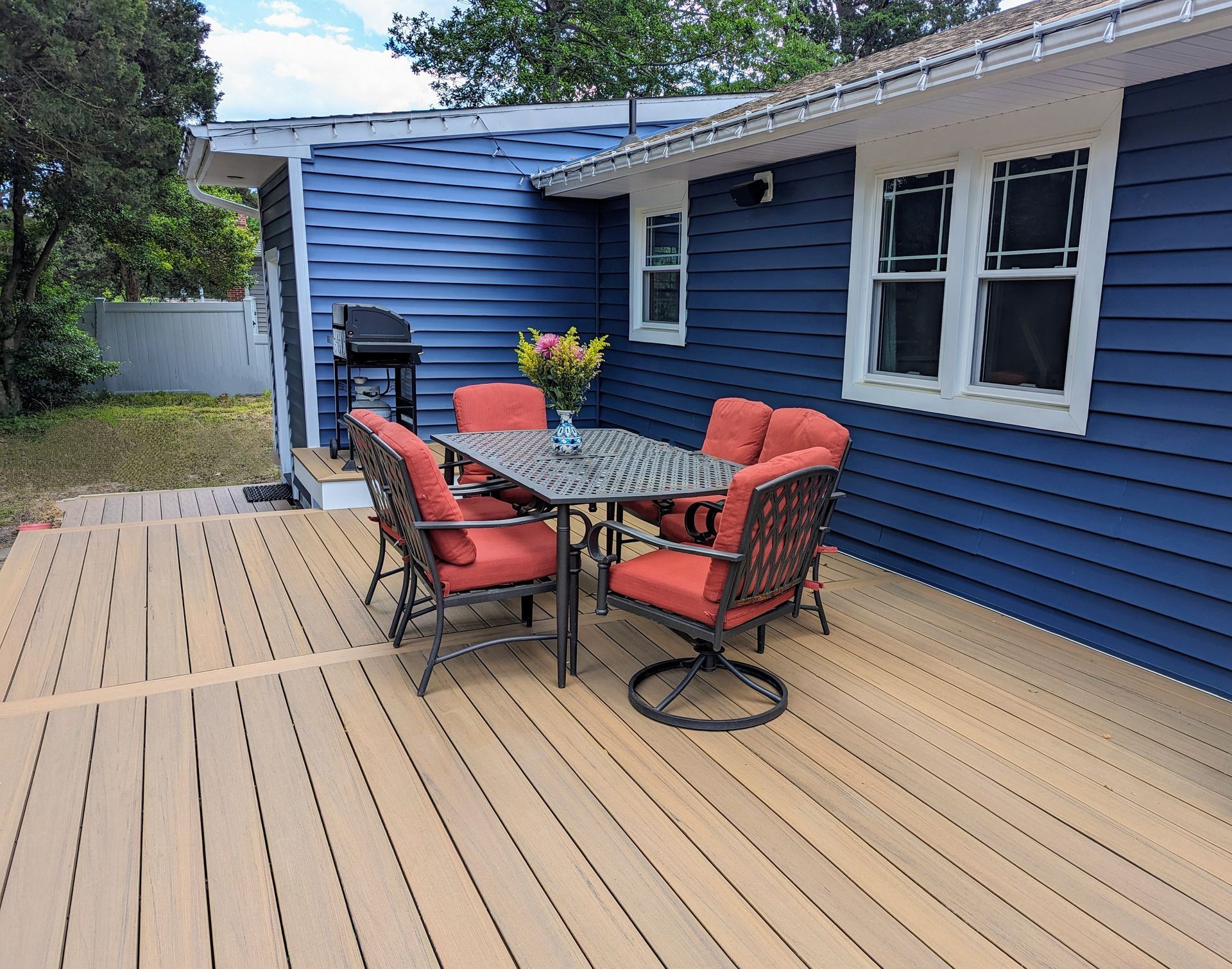 A deck with a table and chairs in front of a blue house