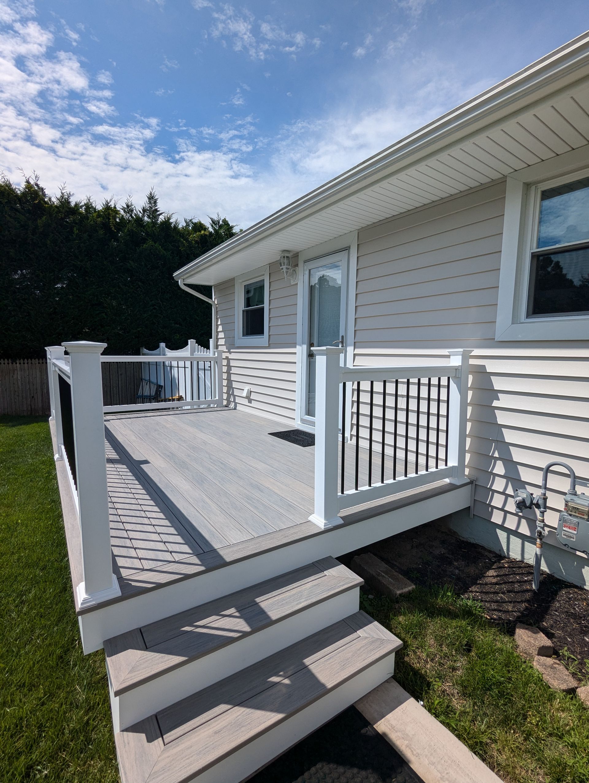 A white house with a large deck and stairs