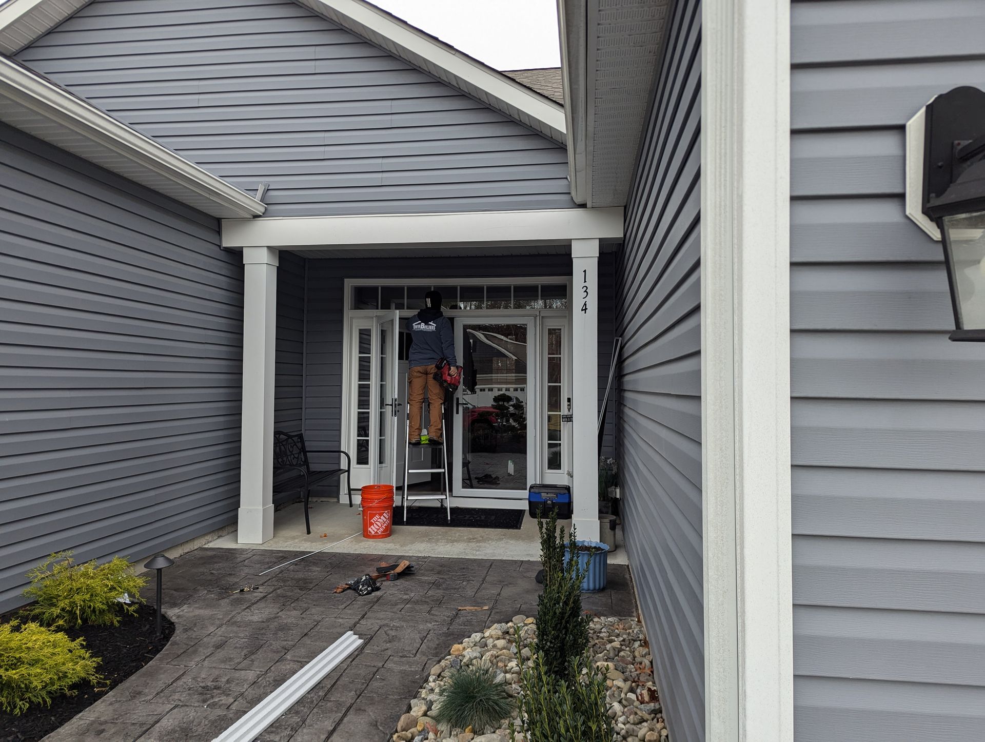 A man is standing on a ladder in front of a house.