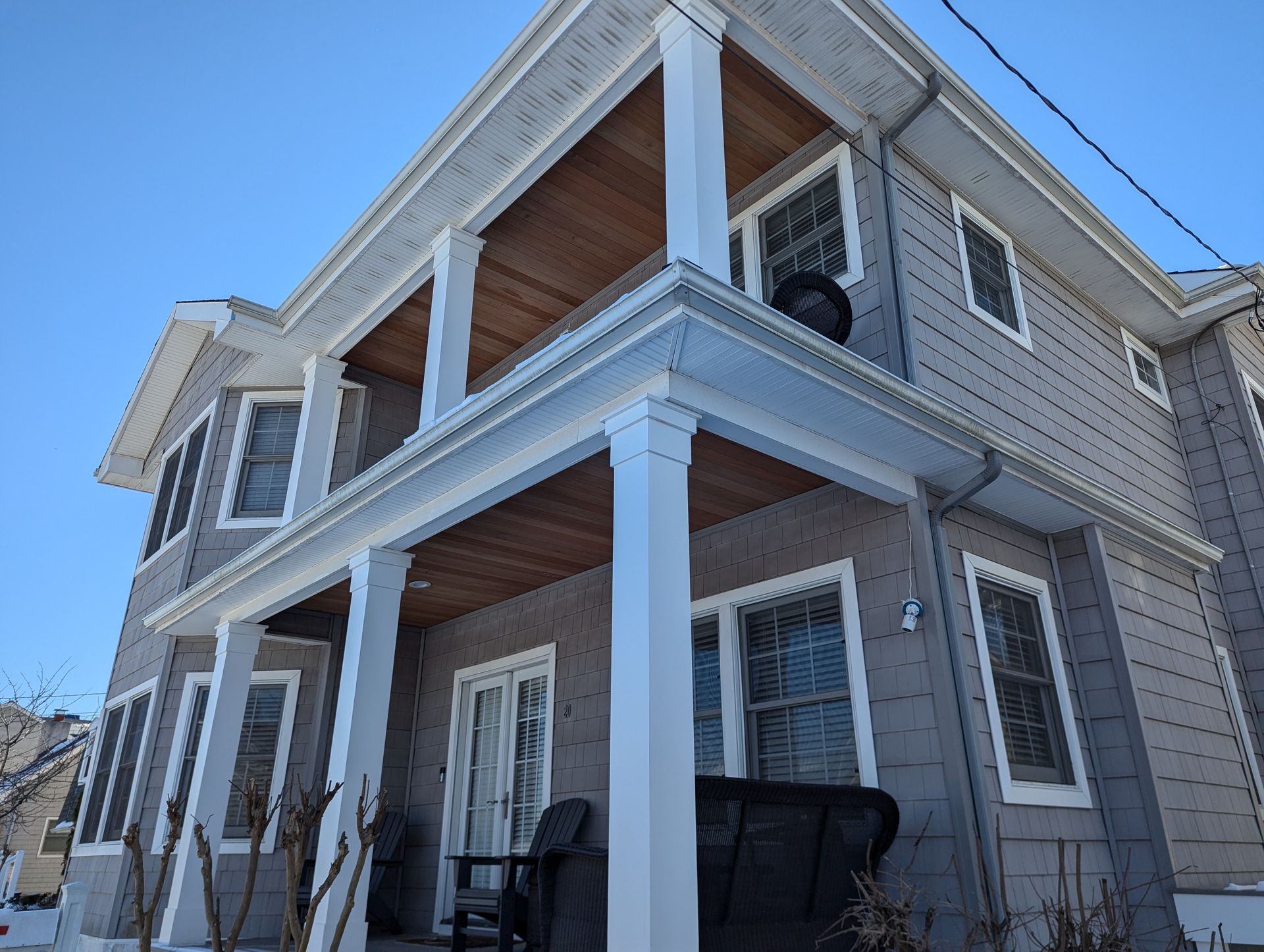 A large house with a porch and a black trash can in front of it