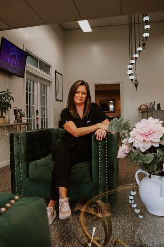 A woman is sitting in a green chair in a living room.