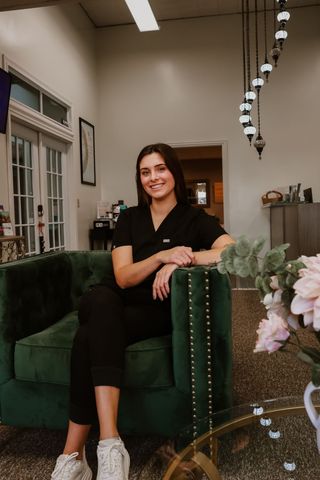 A woman is sitting in a green chair in a room.