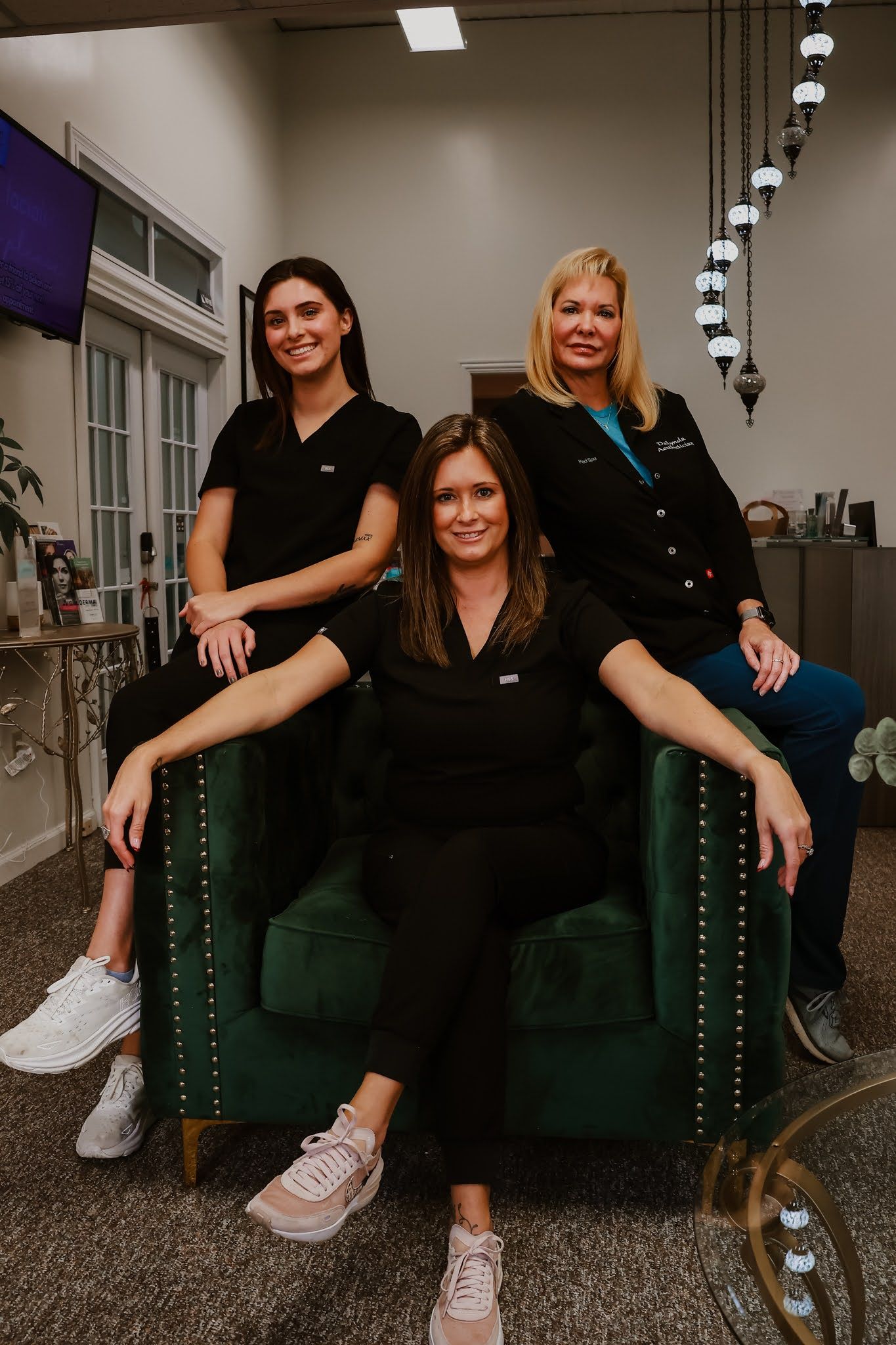 Three women are posing for a picture while sitting on a green chair.