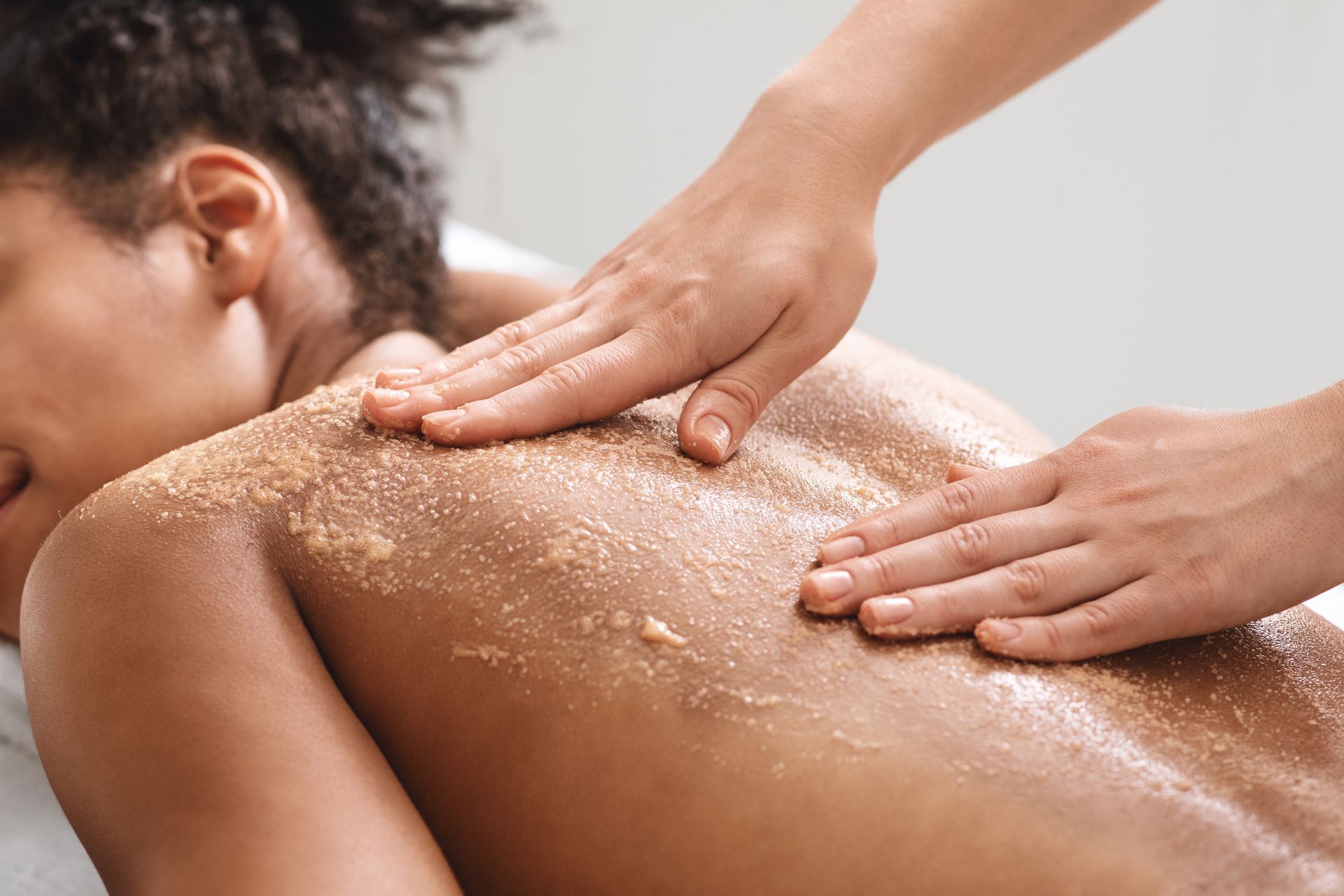 A woman is getting a body scrub massage at a spa.