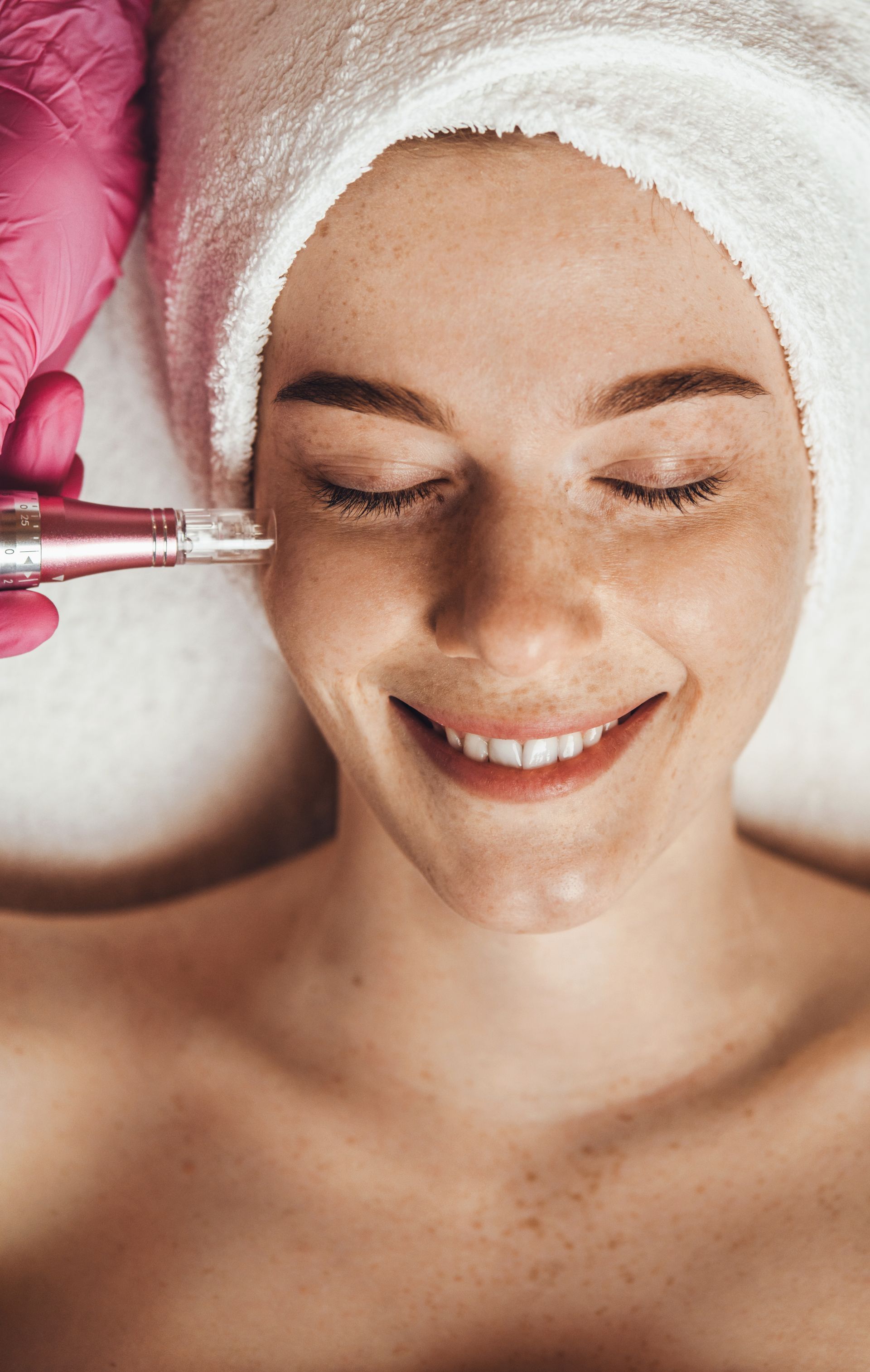 A woman with a towel wrapped around her head is getting a facial treatment.
