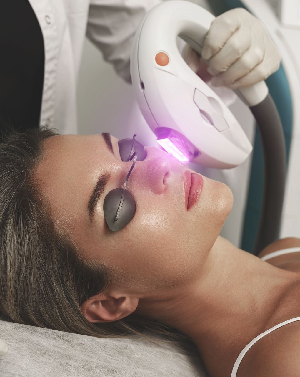 A woman is getting a laser treatment on her face.