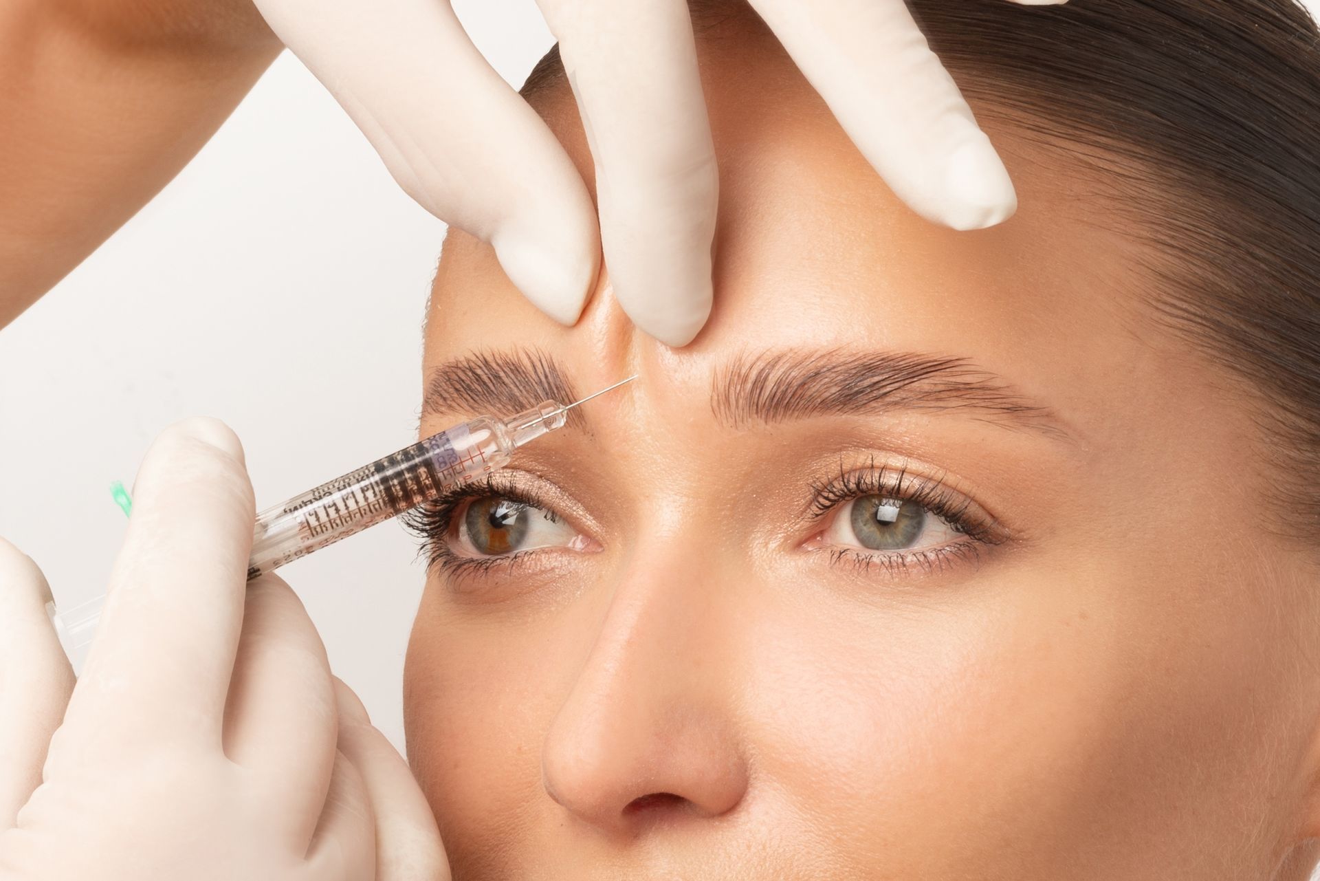A woman is getting a botox injection in her forehead.