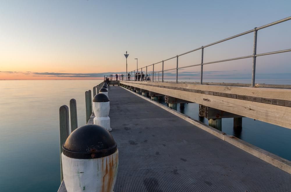 A Pier With a Railing Leading Into the Ocean at Sunset — NLJ Partners P/L In Wyong, NSW