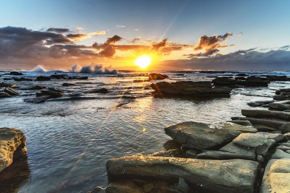 Sunset Over A Rocky Coastline With Crashing Waves — NLJ Partners P/L In Wyong, NSW