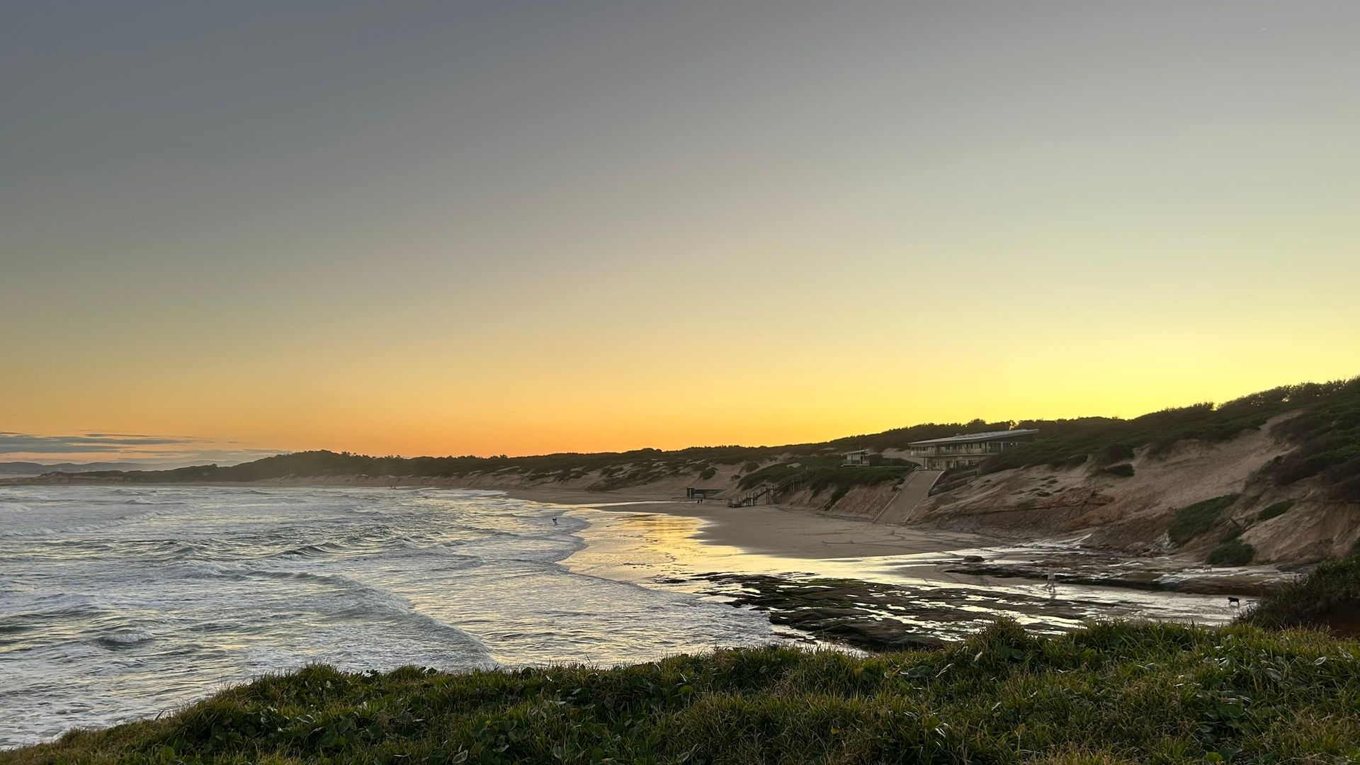 Beach At Sunset With Houses On The Hill, And Water With Waves — NLJ Partners P/L In Wyong, NSW