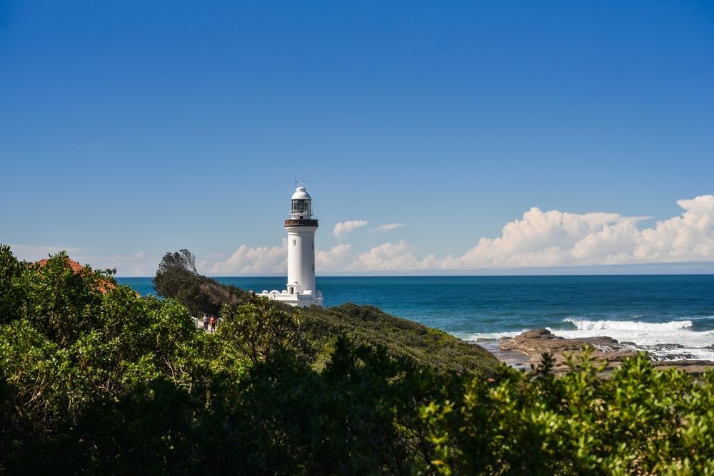 A lighthouse is sitting on top of a cliff overlooking the ocean — NLJ Partners P/L In Wyong, NSW