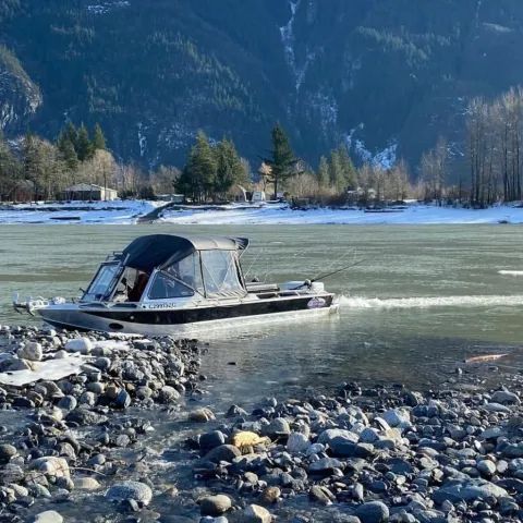 A boat is going down a river with mountains in the background.