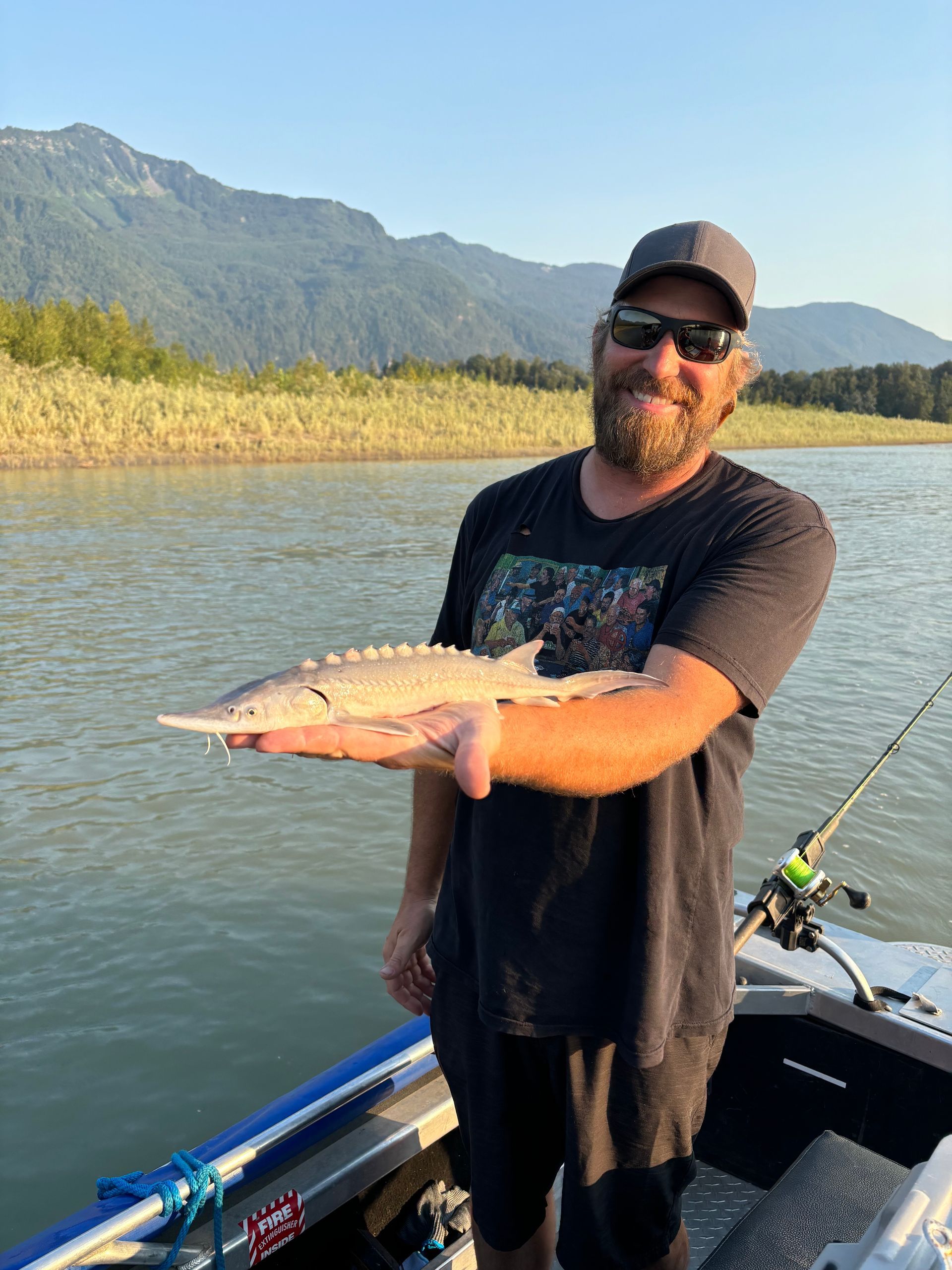 man on boat holding juvenile sturgeon