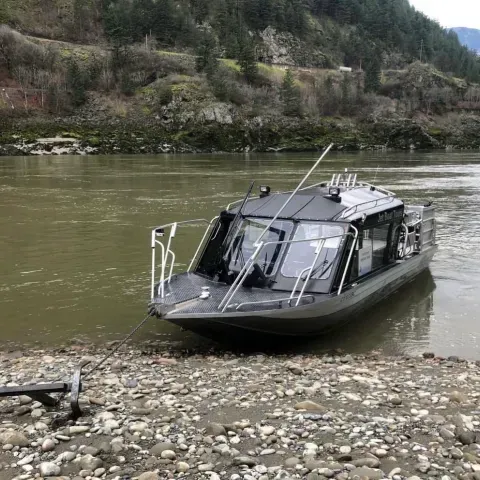 A small boat is sitting on the shore of a river.