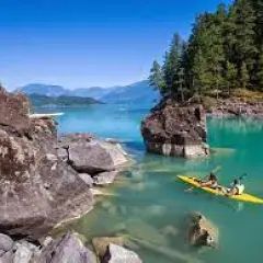 A couple of people are kayaking on a lake surrounded by rocks.