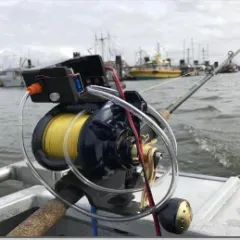 A fishing reel is attached to a fishing rod on a boat.