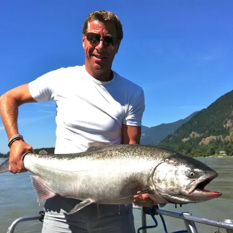 A man in a white shirt is holding a large fish