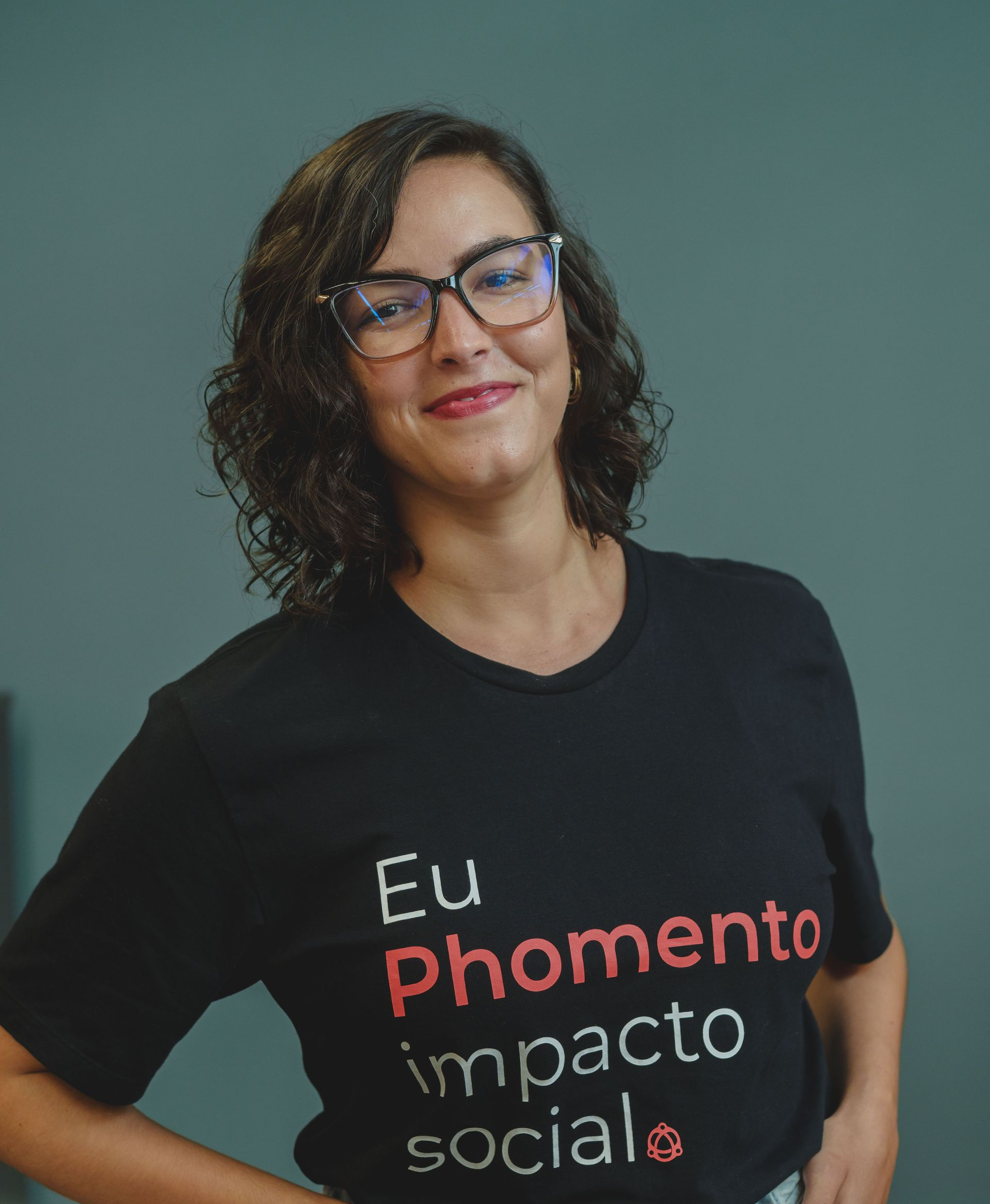 Mulher de cabelos castanhos e camisa preta sorri para a câmera.