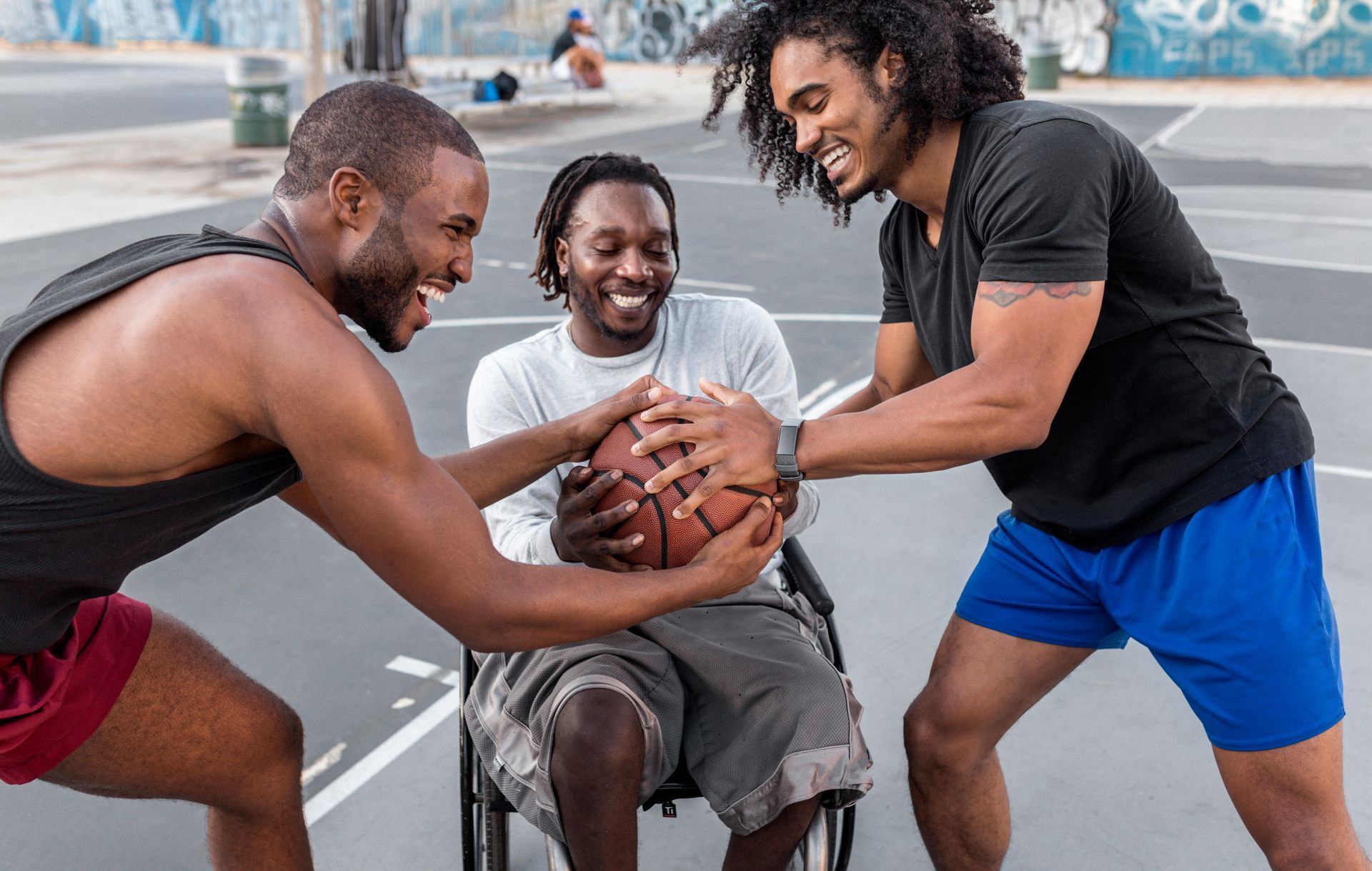 Três pessoas sorrindo e segurando uma bola de basquete juntas em uma quadra de basquete ao ar livre.
