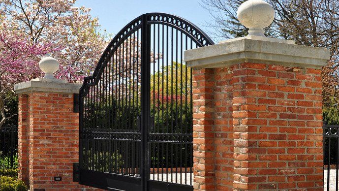 A finely wrought steel gate between brick pillars