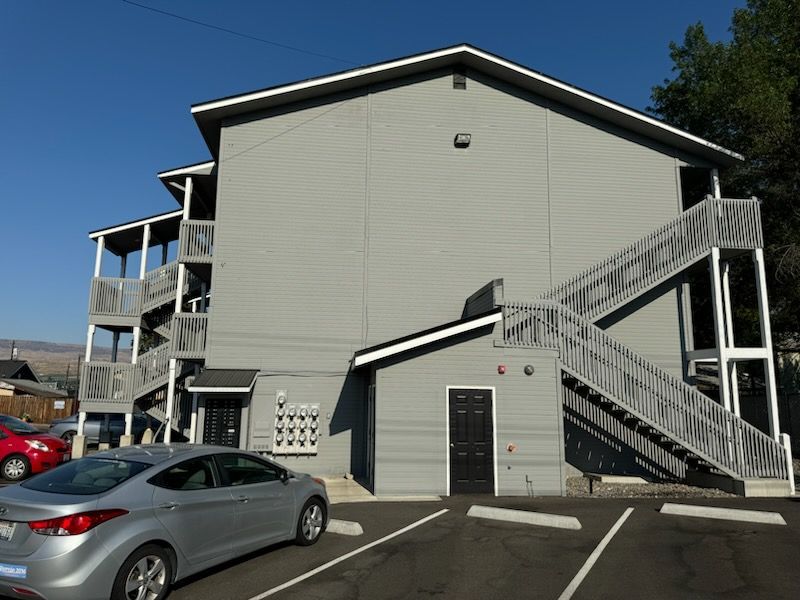 A silver car is parked in front of a building with stairs