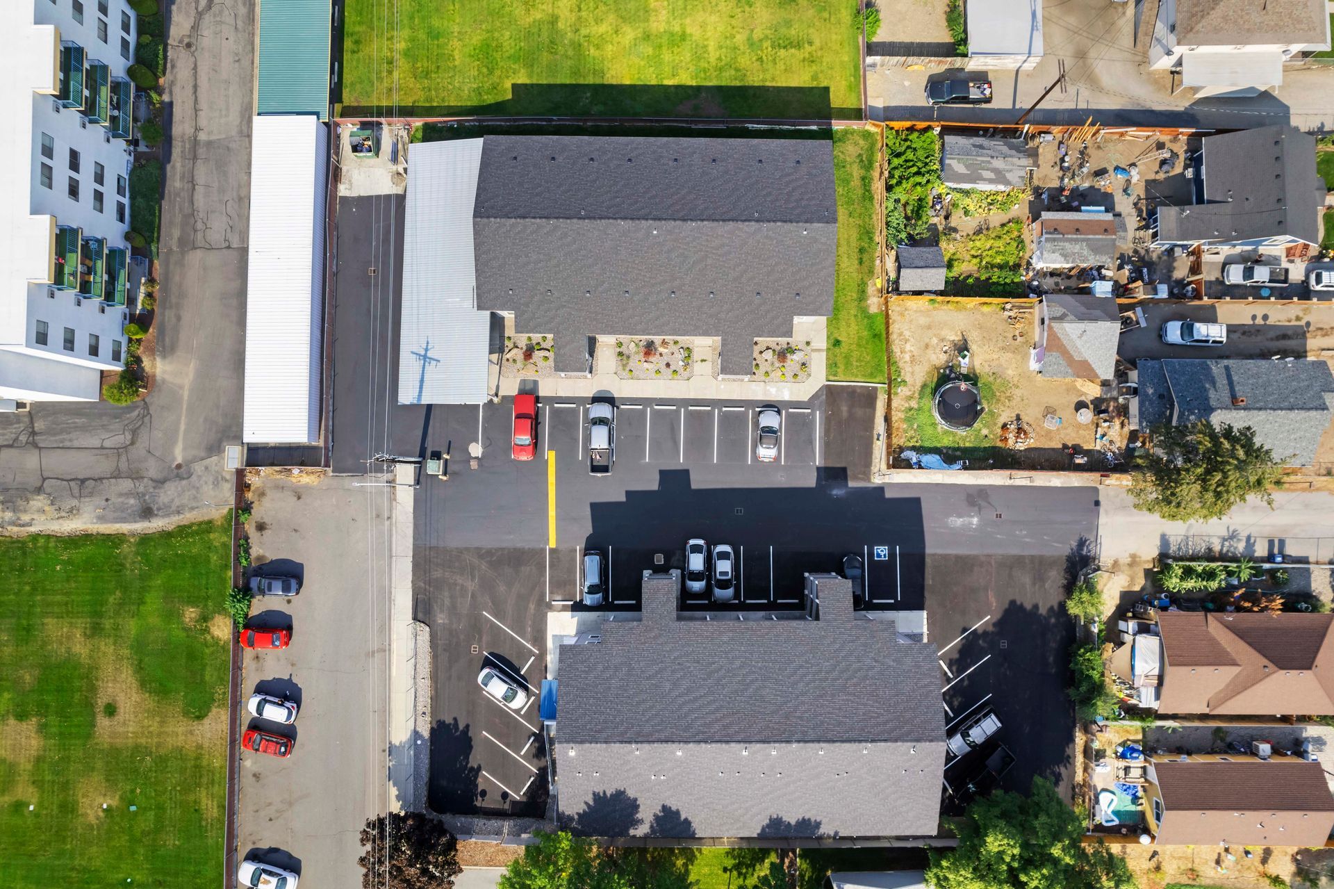 An aerial view of a parking lot with cars parked in front of a building.