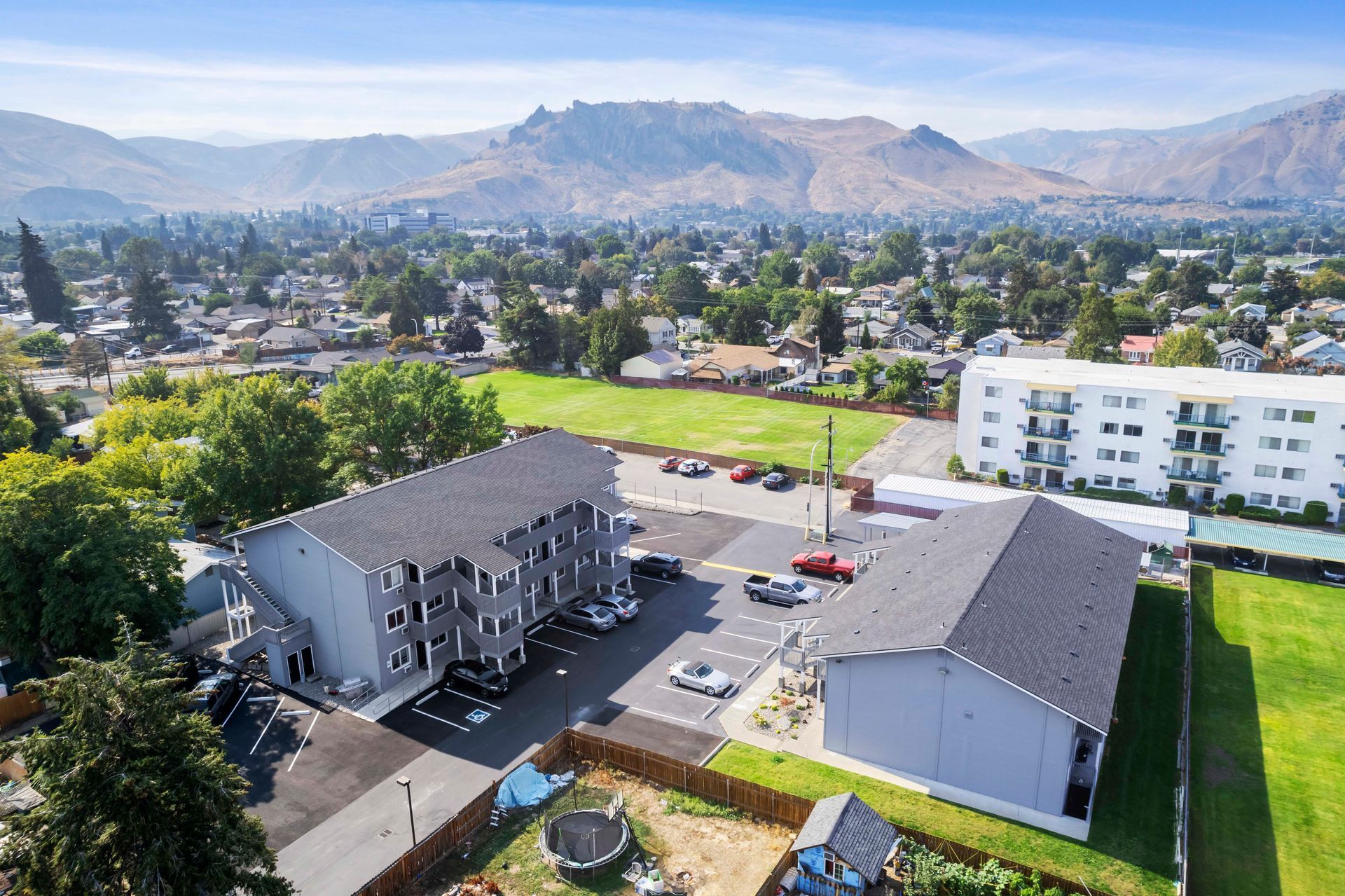 An aerial view of a large apartment building with mountains in the background.
