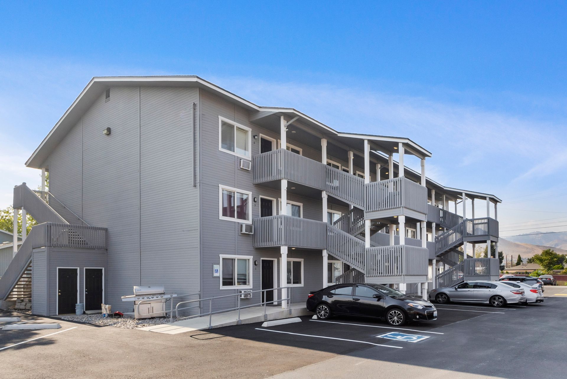 A large apartment building with cars parked in front of it.