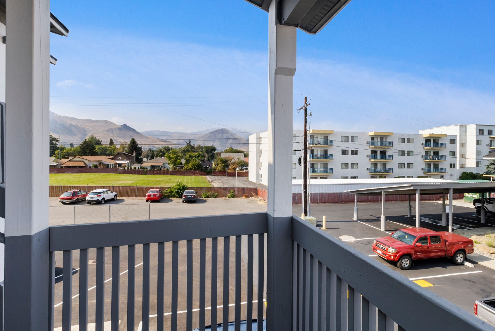 A red truck is parked in a parking lot on a balcony overlooking a parking lot.