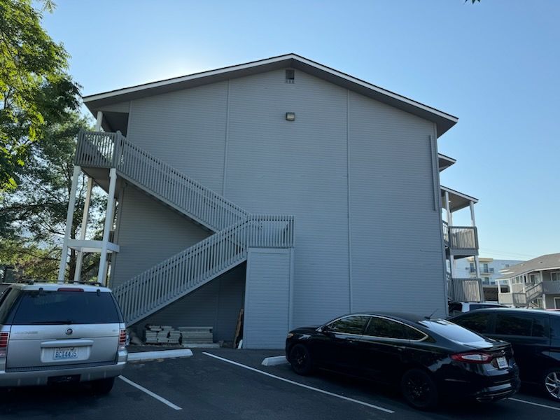 A building with stairs and cars parked in front of it