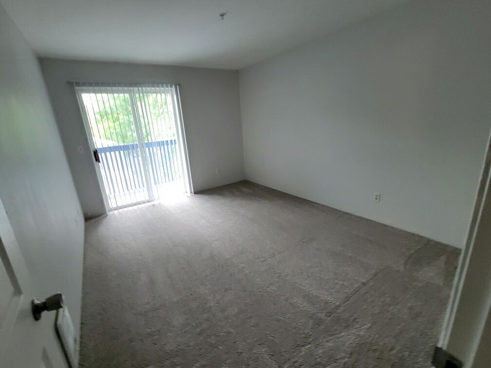 An empty room with a sliding glass door and a balcony.