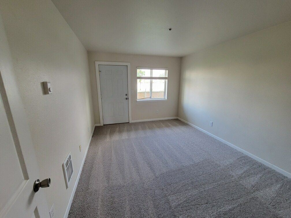 An empty living room with a door and a window.