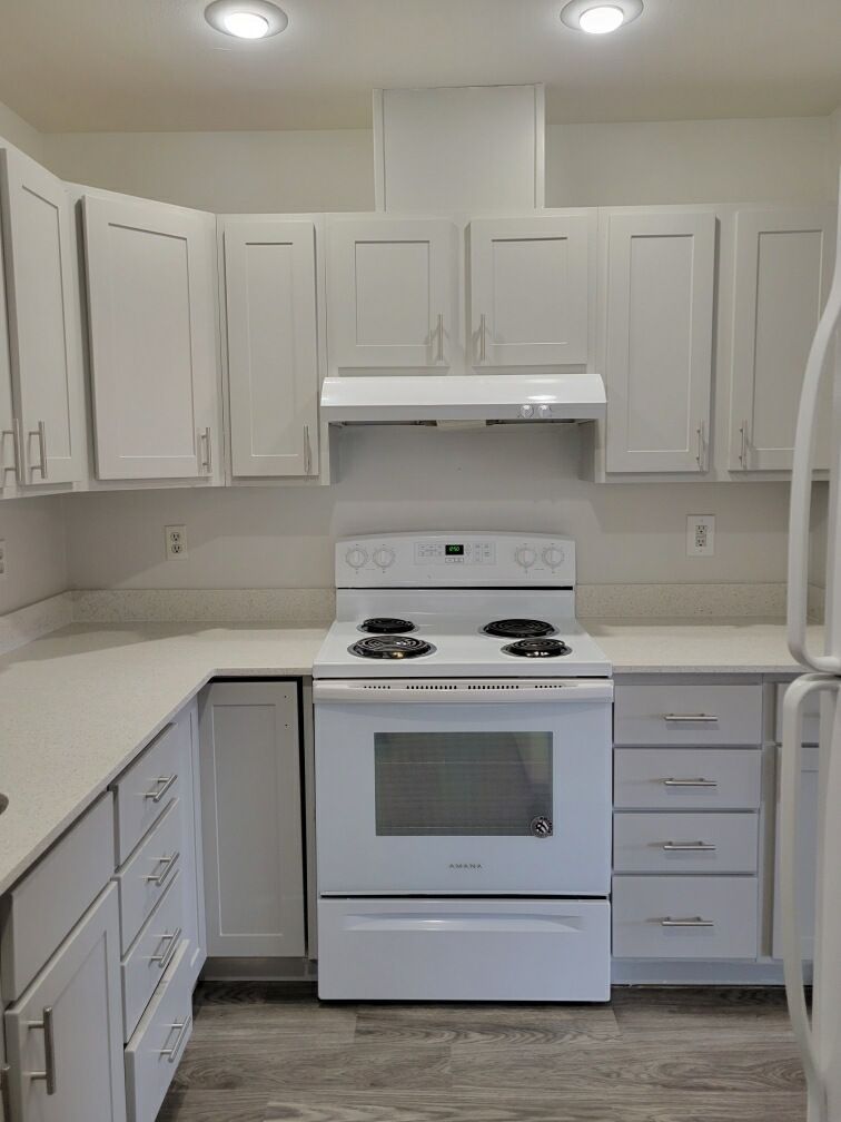 A kitchen with white cabinets , a stove and a refrigerator.