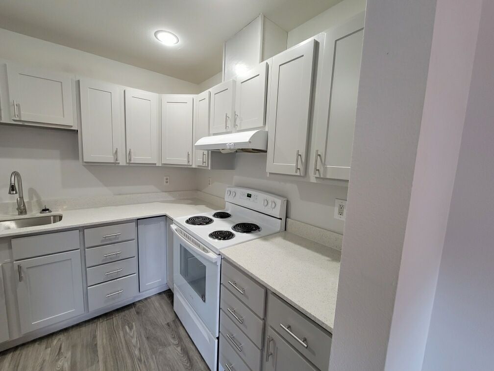 A kitchen with white cabinets , white appliances , and a sink.