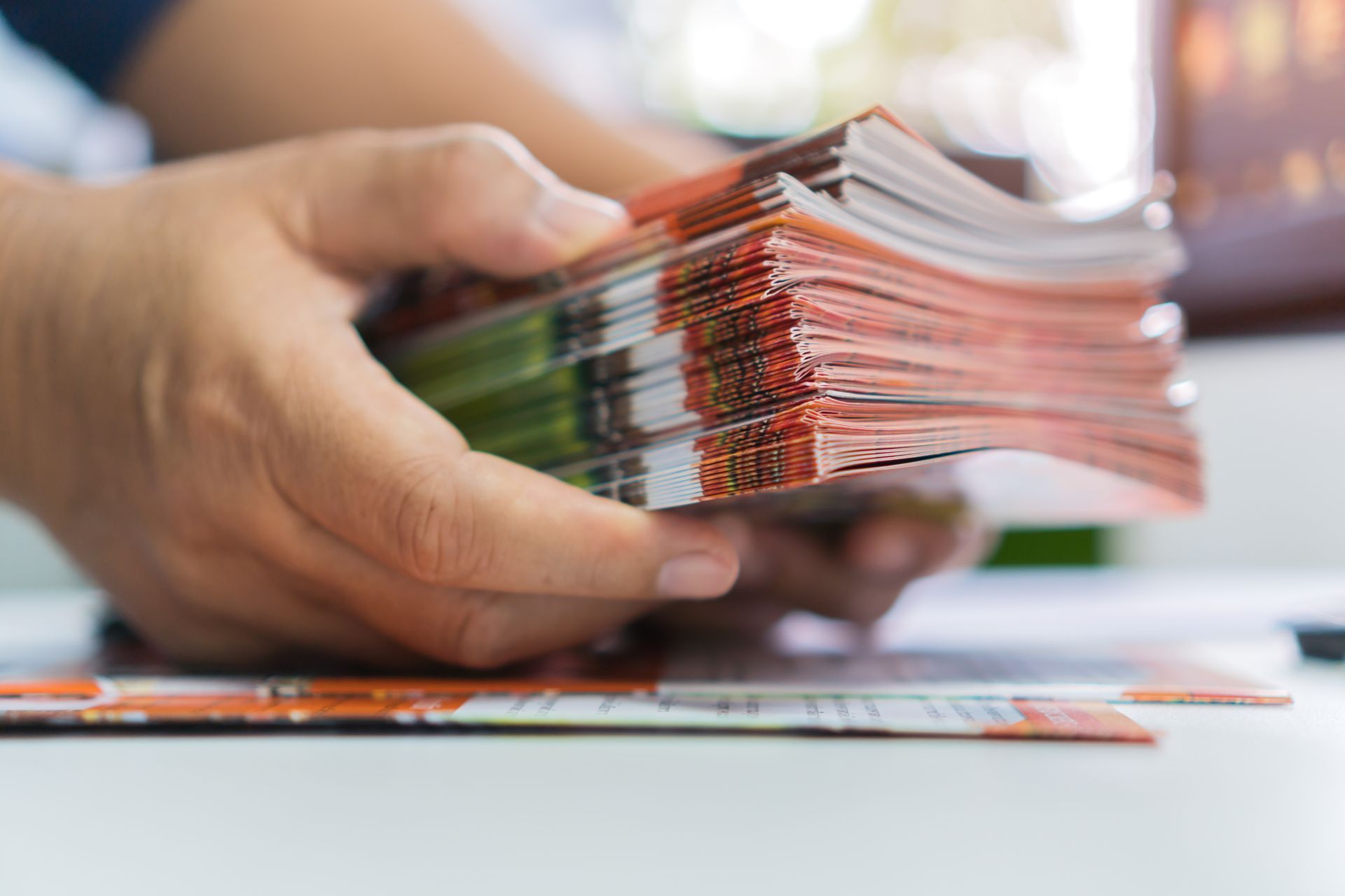 Close-up of a stack of brochures being handled and organized by a person.