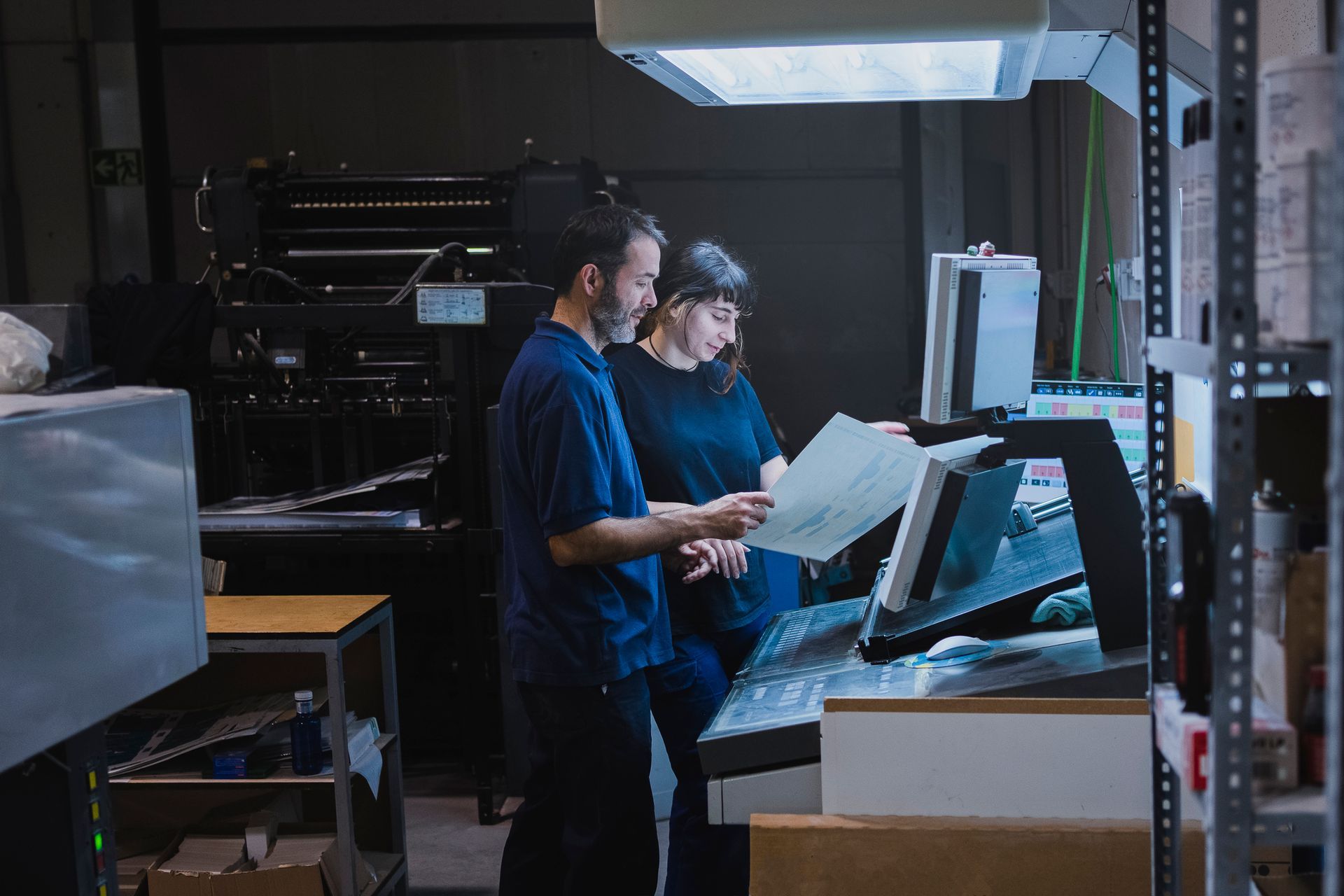A man and a woman are working on a machine in a factory.