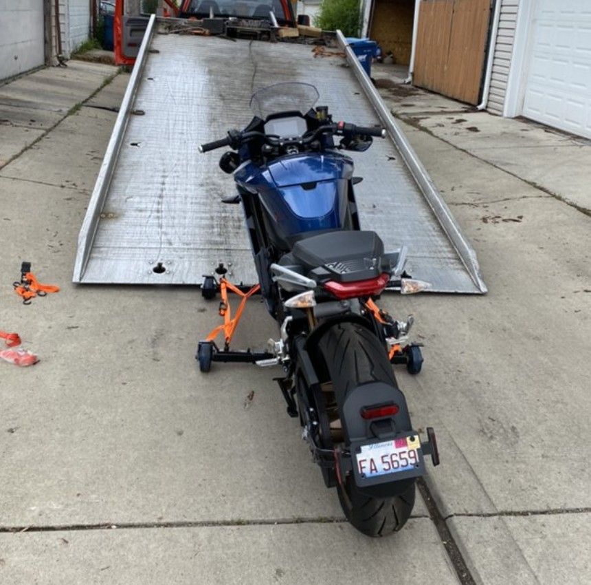 Motorcycle in front of a flatbed tow truck.